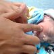 Bebe prematuro y la mano de un terapeuta estimulando su reflejo de succion