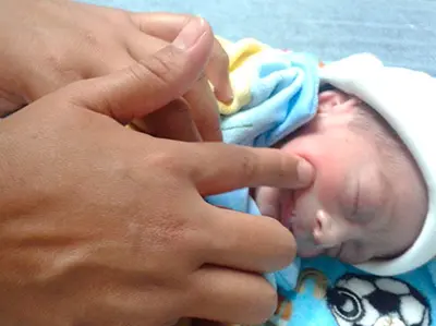 Bebe prematuro y la mano de un terapeuta estimulando su reflejo de succion