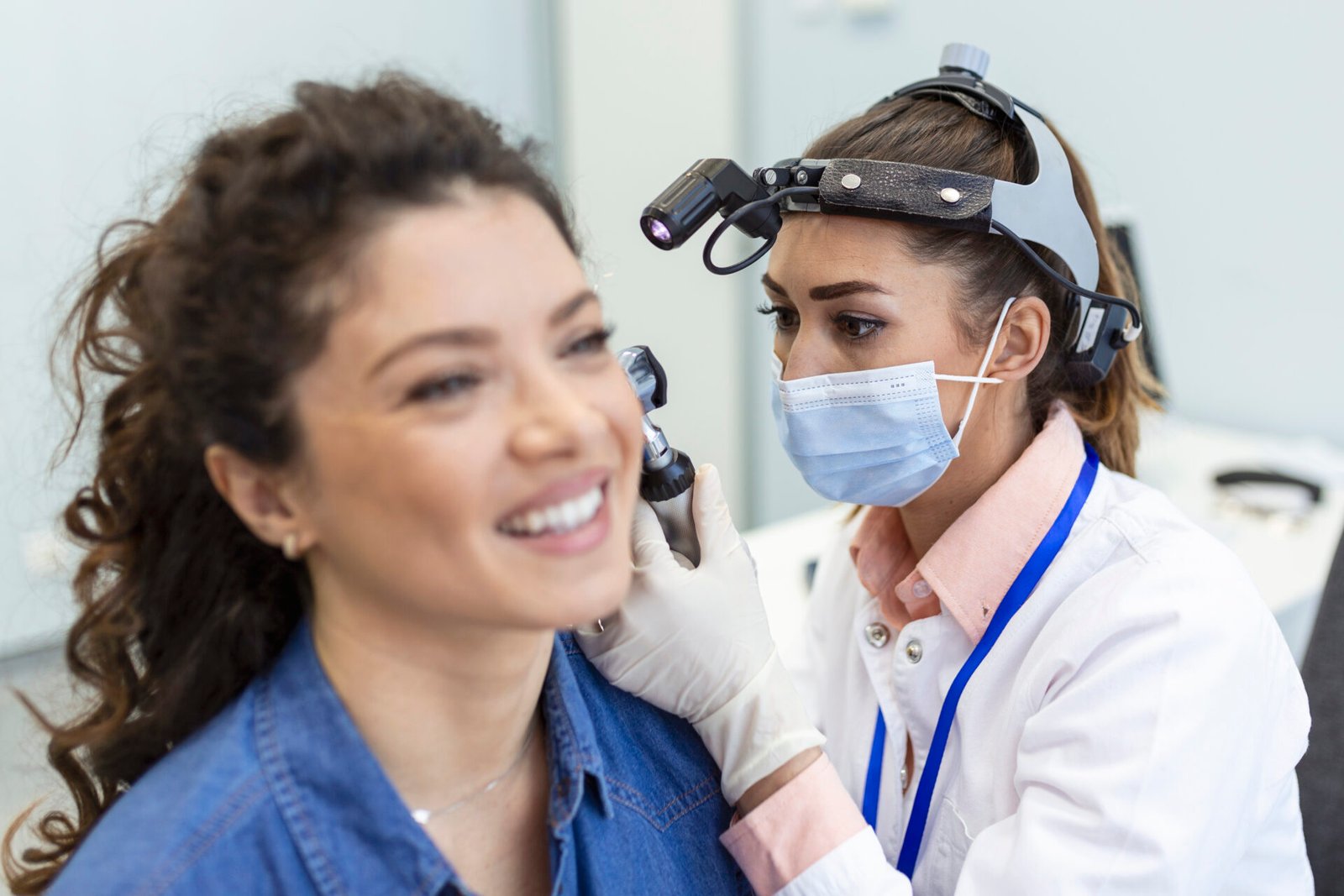 Hearing exam. Otolaryngologist doctor checking woman’s ear using otoscope or auriscope at medical clinic.